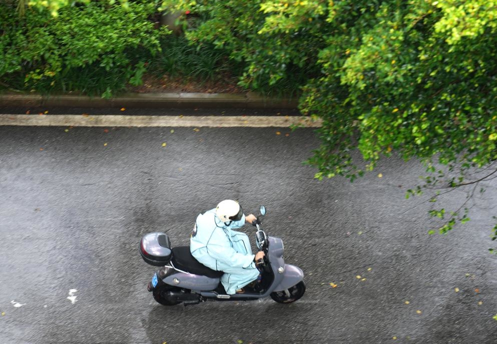 7月24日，市民在广西南宁街头冒雨骑行。新华社记者 周华 摄