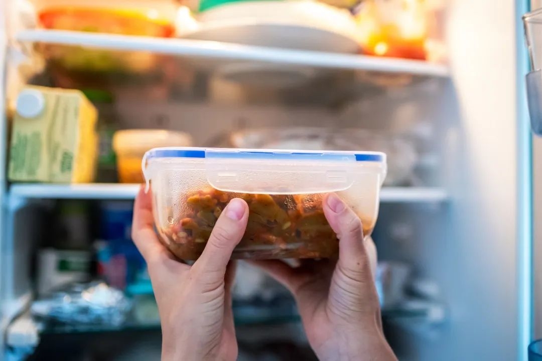 一个不知名的女人把装满食物的盘子放进冰箱图片素材
